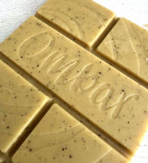 Photo of an unwrapped Ombar Blonde caramalised white chocolate bar. It's a light caramel colour, flecked with vanilla, and has 'Ombar' stamped on it.
