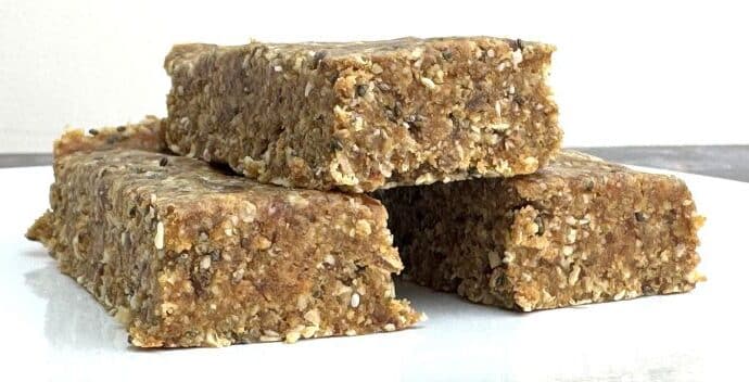 a small white plate with a pyramid of three seedy, oaty protein bars